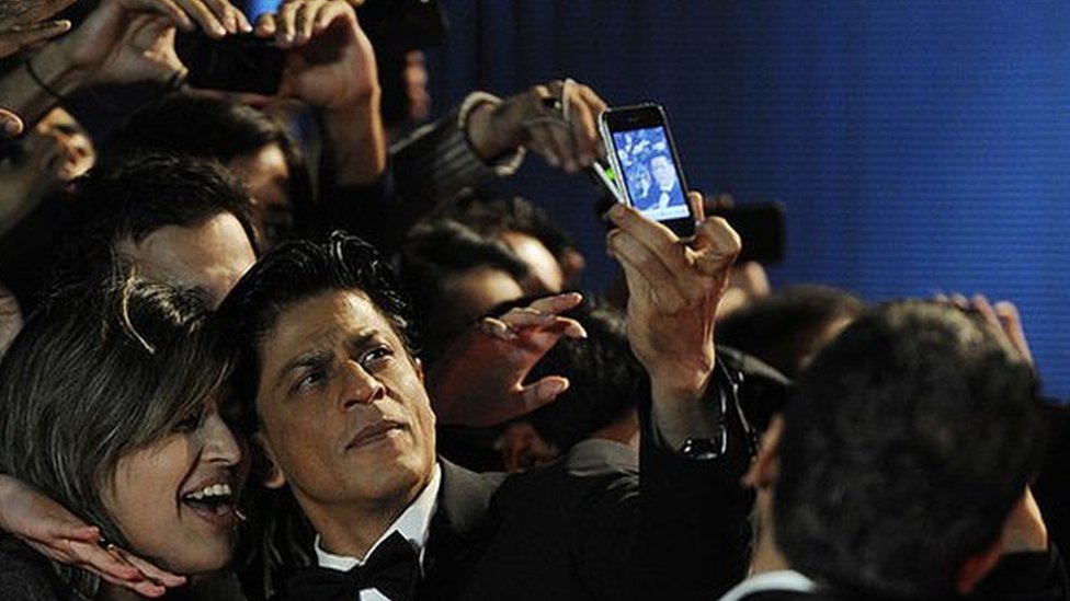 Aktor Shah Rukh Khan berpose dengan penggemar.