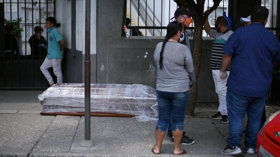 People surrounding a coffin on the street