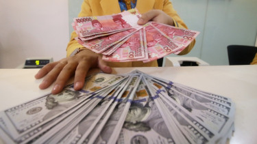 Petugas bank tunjukkan uang rupiah dan dolar Amerika Serikat.