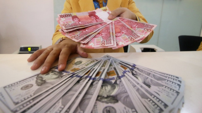 Petugas bank tunjukkan uang rupiah dan dolar Amerika Serikat.